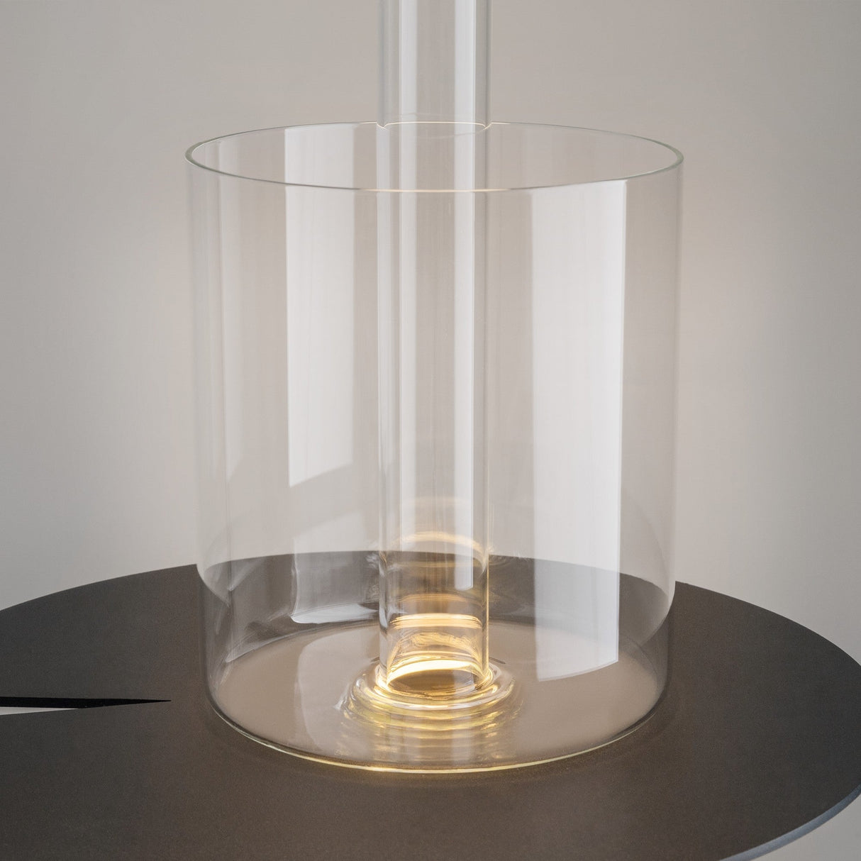 Featuring a sleek, cylindrical design, the AI Collaboration Rechargeable LED Table Lamp emits a warm glow from its clear central column. Its minimalist appeal is enhanced by a black base and reflective glass vase for an elegant ambiance.