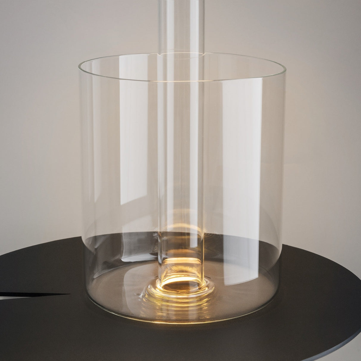 An AI Collaboration Rechargeable LED Table Lamp With Glass Vase in white, featuring a tall, narrow center tube, sits on a black surface. Its soft, warm light creates a serene ambiance at the base of the elegant cylindrical vase.