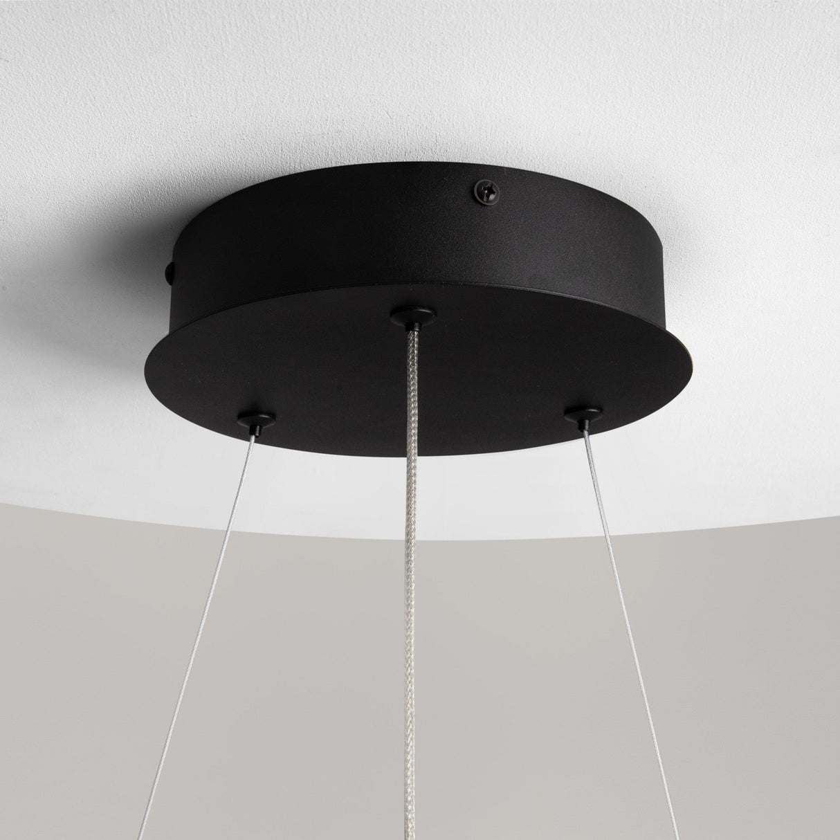 A black ceiling mount with a matte finish and three thin wires supports the Curve LED Dimmable Spiral Suspension Light, embodying modern design. Its adjustable color temperature effortlessly enhances any space.