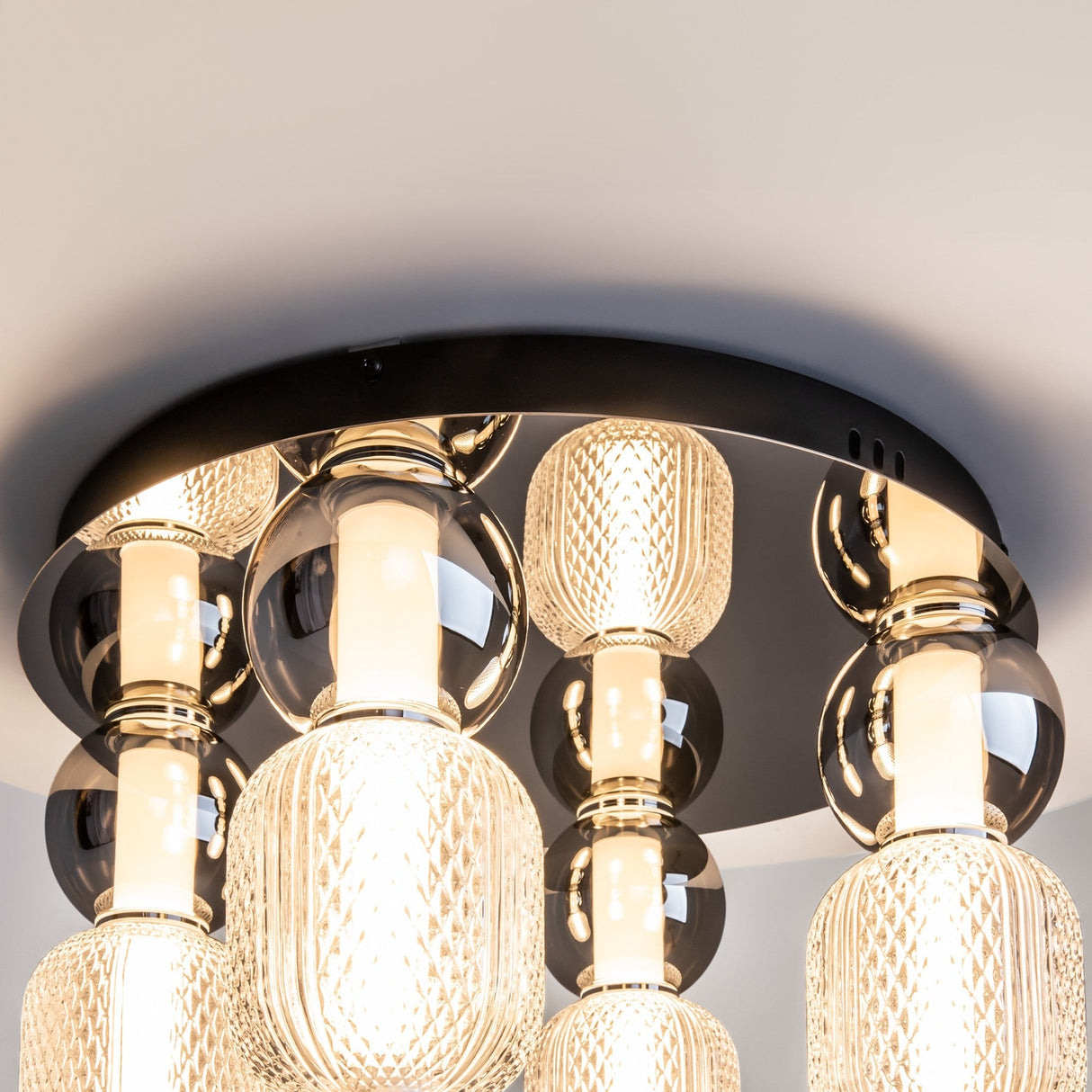The Drop LED Flush Light 3000K - Chrome features multiple intricately patterned glass shades on a sleek chrome base, emitting warm ambient light to enhance contemporary spaces with style and elegance.