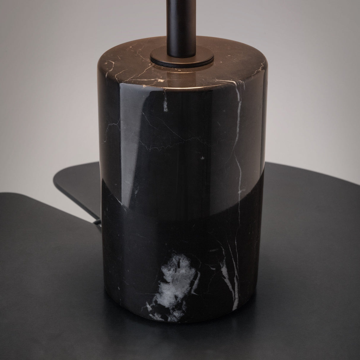 The Mystic LED Table Lamp - Black With Marble Base showcases a detailed close-up of its sleek black marble base with subtle white veining, resting on a dark surface. Its modern elegance is perfectly complemented by a spherical glass shade above.