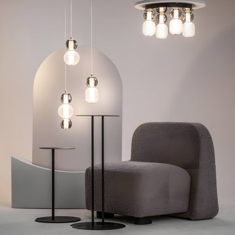 A modern interior featuring a gray textured armchair, two slim black side tables, and a chic hanging lamp with spherical glass bulbs. The Drop LED Flush Light 3000K - Chrome adds to the contemporary space with a backdrop of geometric shapes in soft gray tones for a minimalist aesthetic.