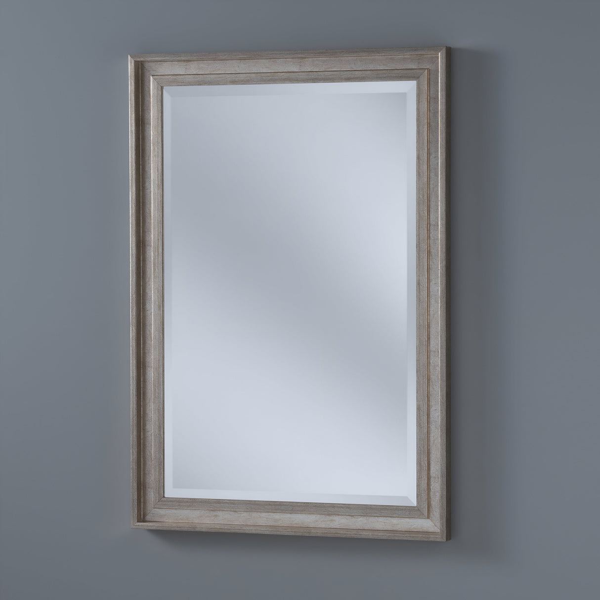 The Artivis Rectangle Wall Mirror - Silver hangs gracefully on a solid gray wall. Its sleek silver frame and subtle reflection of light gray surfaces enhance its minimalistic design, making it a perfect home decor piece.