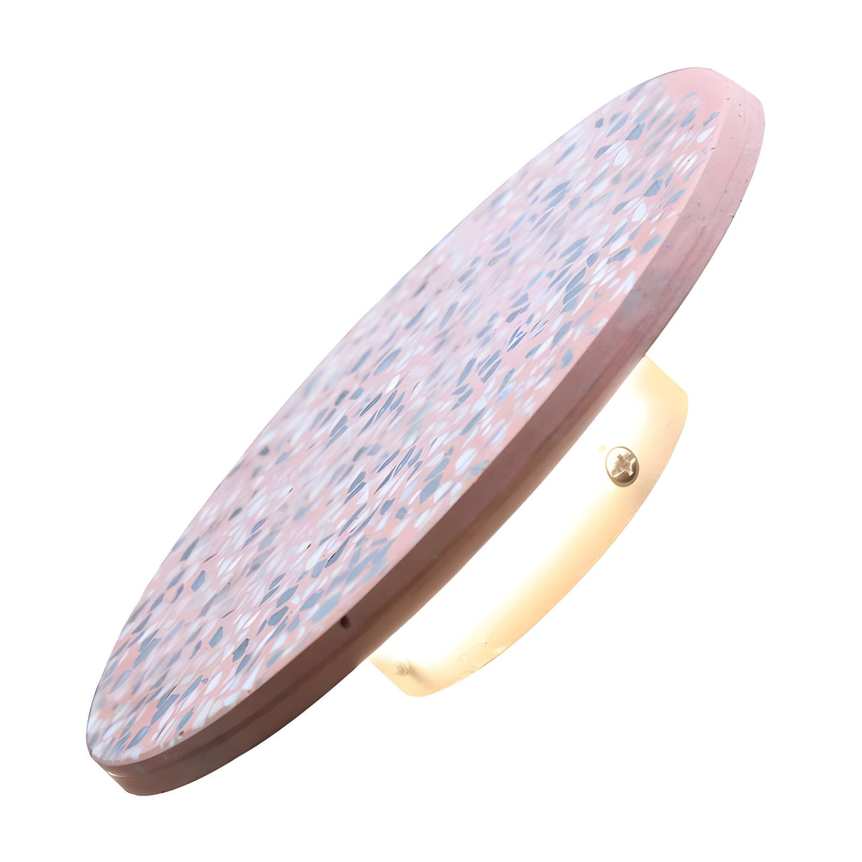 The Pin LED Wall Light is a round, pink terrazzo sconce with a speckled pattern, mounted on a brass fixture. Its disk shape casts a soft, ambient halo glow from behind, reflecting modern minimalist design.