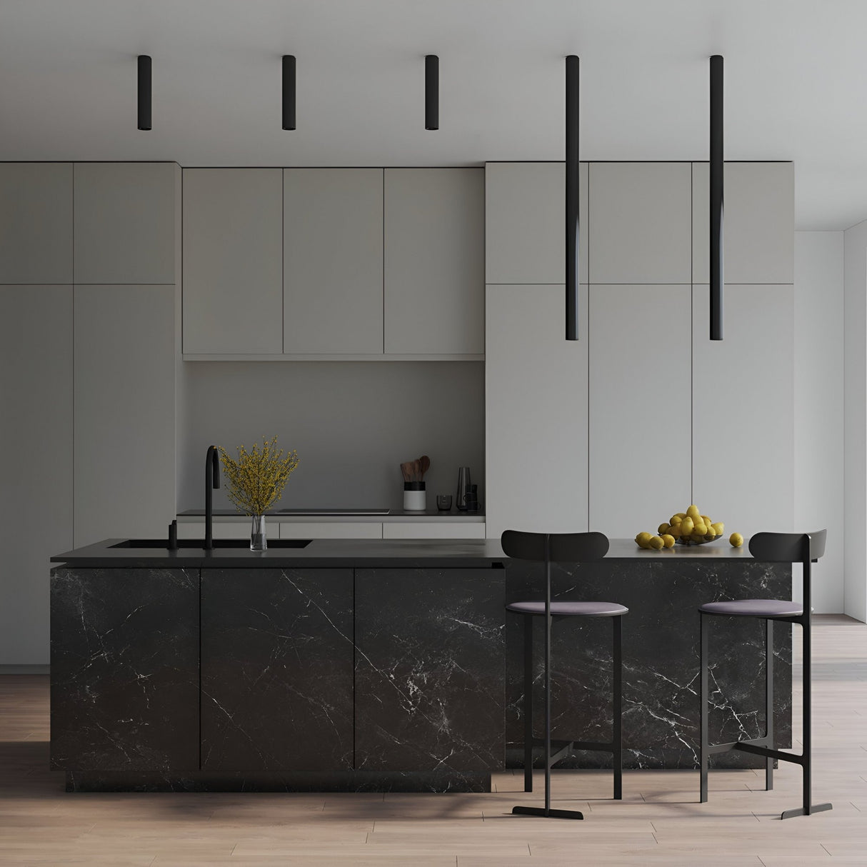 Minimalist kitchen with matte black marble island, two modern bar stools, built-in cabinets, and the Pulcra Tube Ceiling Light - Black. A vase of yellow flowers and a bowl of lemons decorate the countertop, highlighting true minimalist design.