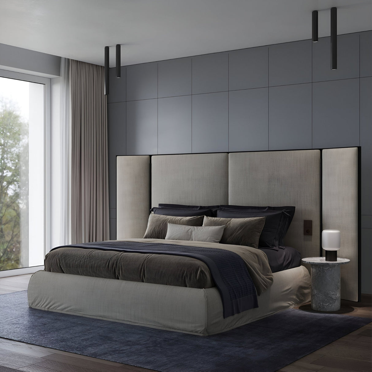 A modern bedroom featuring the Pulcra Tube Ceiling Light - Black, a large upholstered bed with dark bedding, gray wall panels, a marble nightstand, sheer curtains on floor-to-ceiling windows, and a dark blue rug highlights minimalist style and energy efficiency.