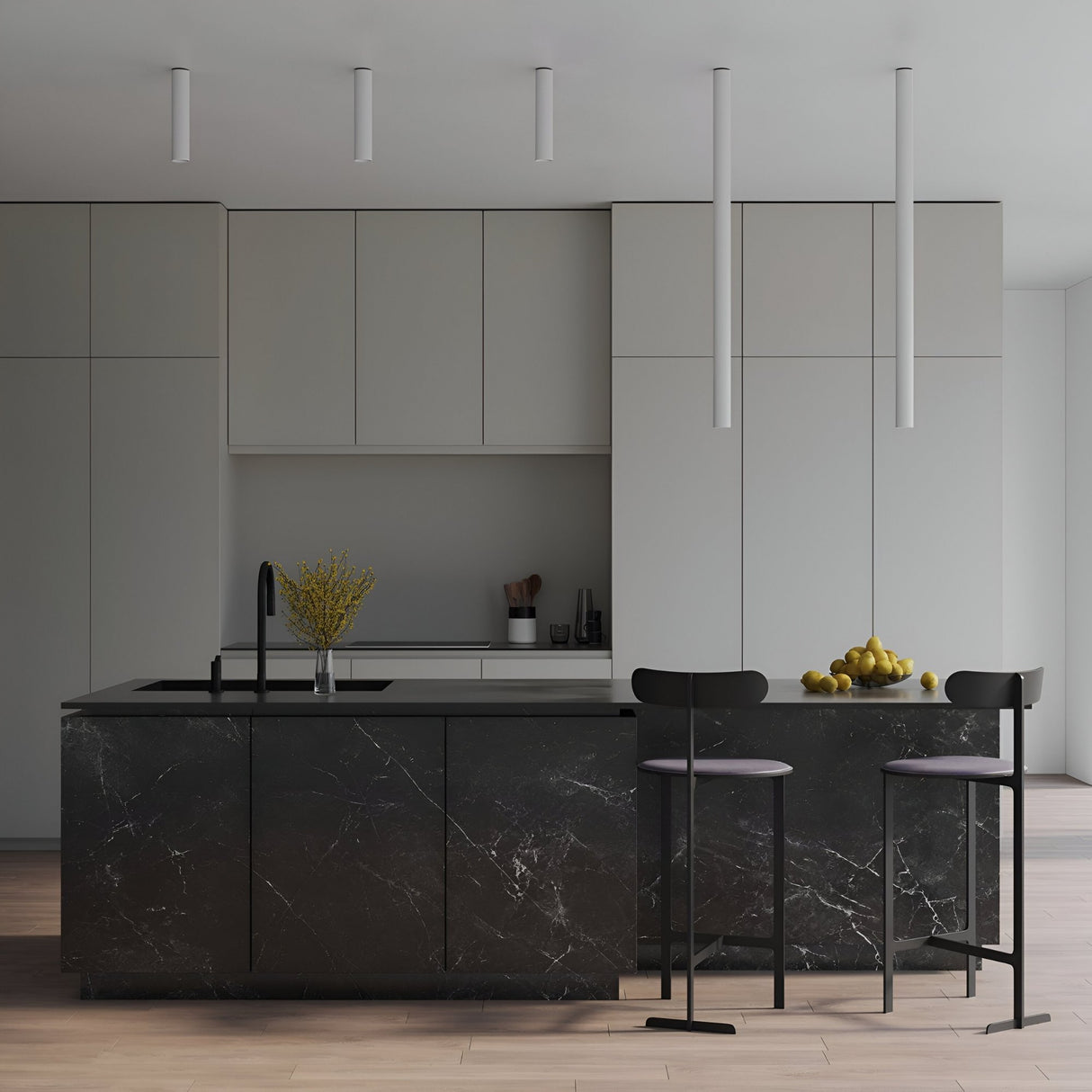 Modern minimalist kitchen with matte grey cabinets, black marble island, two bar stools, and a black sink. Yellow flowers and lemons add color, while four Pulcra Tube Ceiling Lights in white enhance the minimalist elegance.