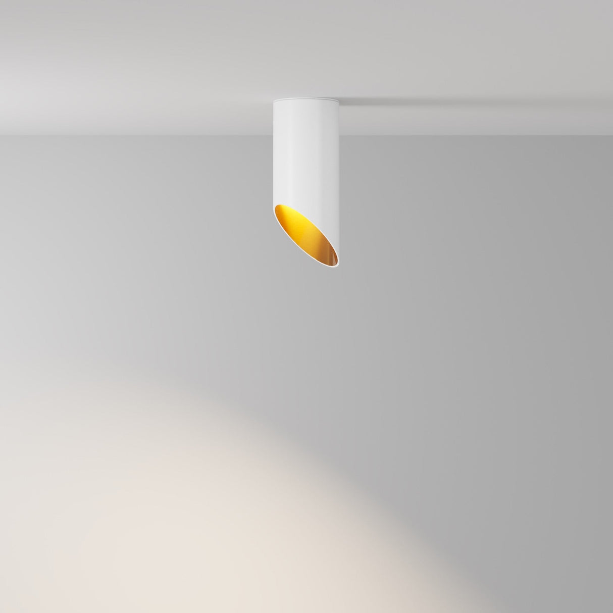 The Lipari Short Surface Mounted Downlight 15cm in White & Gold is a modern lighting fixture with a cylindrical design, featuring a gold reflector that elegantly projects light onto a gray wall.