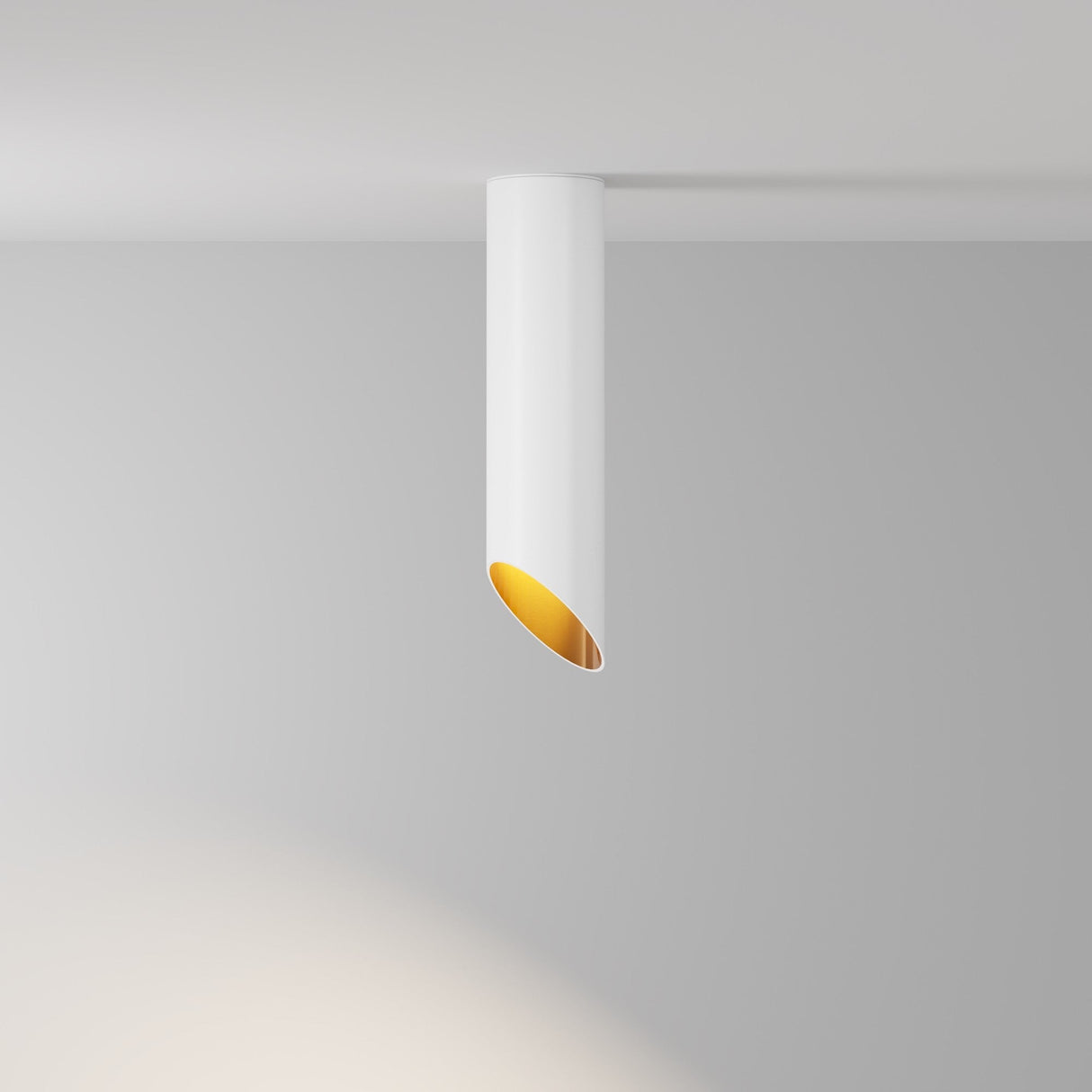 The Lipari Long Surface Mounted Downlight 25cm in White & Gold features a minimalist, cylindrical design with an angled open end. Its gold interior creates a luxurious look while casting soft light on the ceiling and nearby walls, offering a modern minimalist lighting solution.