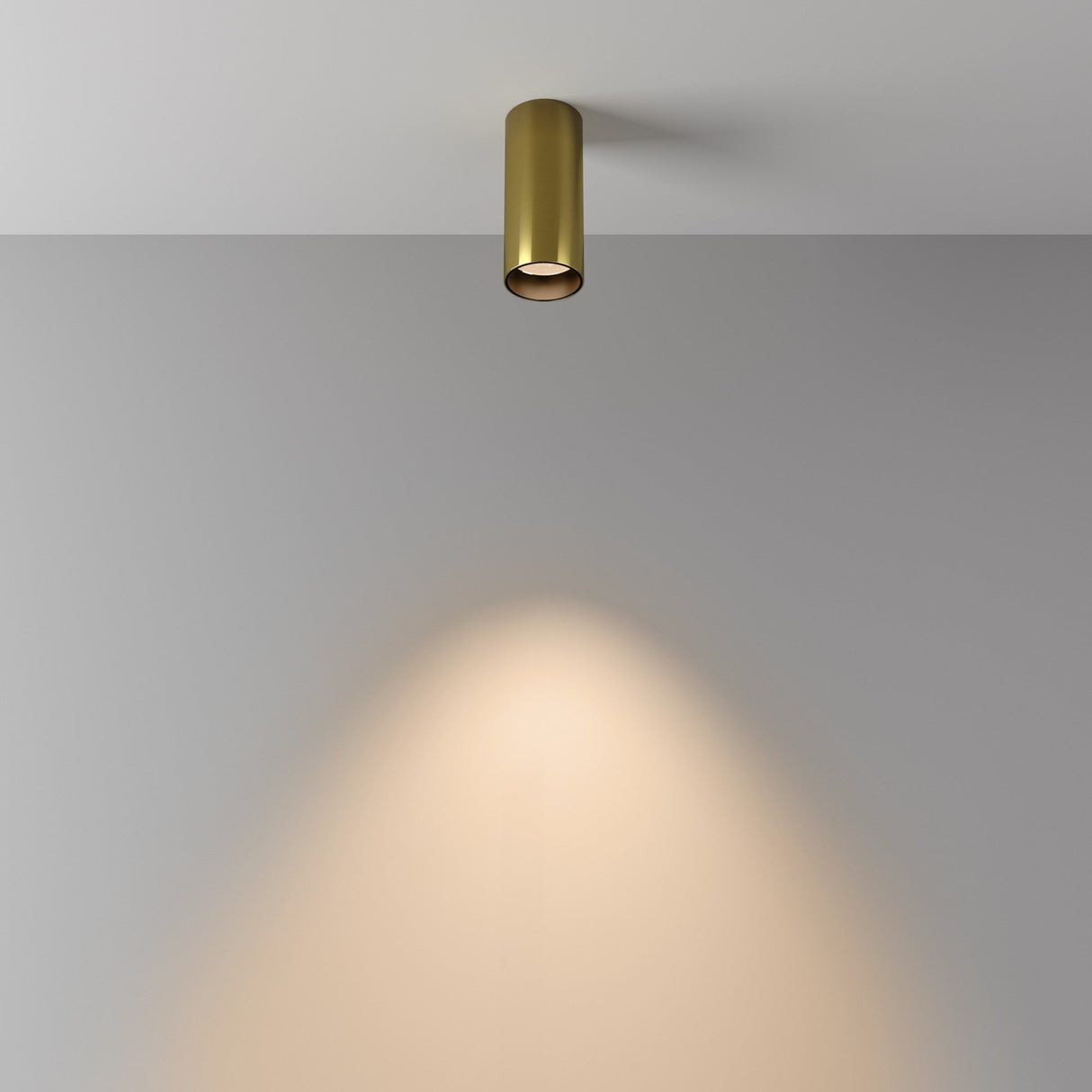 The Focus LED Fixed Round Surface Mounted Downlight 12W 3000K - Brass casts a warm glow on a plain white wall, creating soft, circular illumination. Its simplicity highlights the elegance of this minimalistic, energy-efficient light fixture.