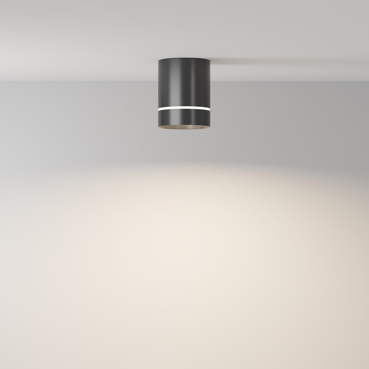 The Orlo LED Round Surface Downlight 9W 4000K in black is modern and cylindrical, surface-mounted on a smooth, light-colored ceiling. This energy-efficient fixture casts a soft, circular glow onto the beige wall below.
