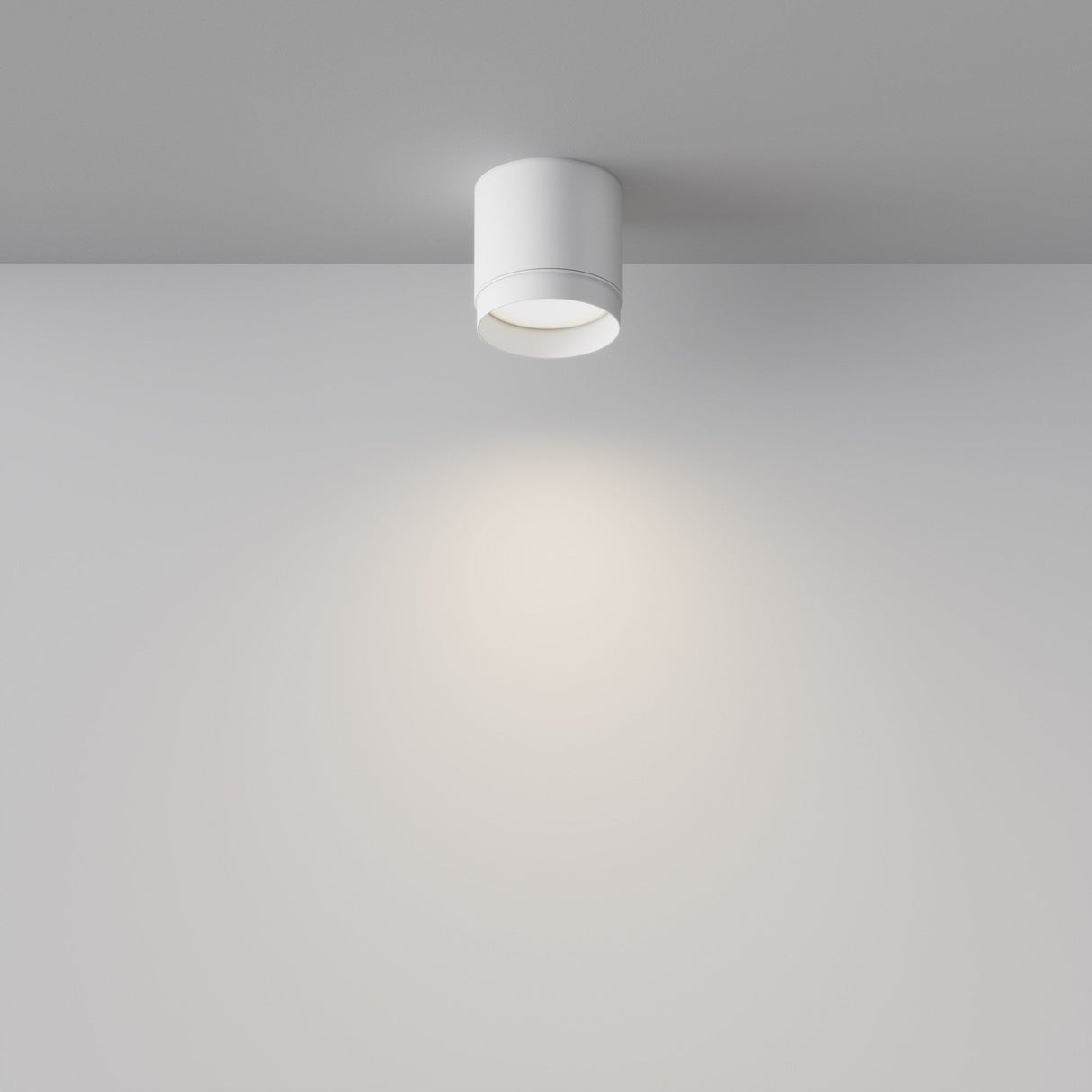 The Polar Round Surface Downlight - White is a modern cylindrical ceiling fixture with a white finish, designed to mount on flat ceilings. It emits a soft, circular glow, enhancing the rooms minimalist aesthetic and lighting versatility.