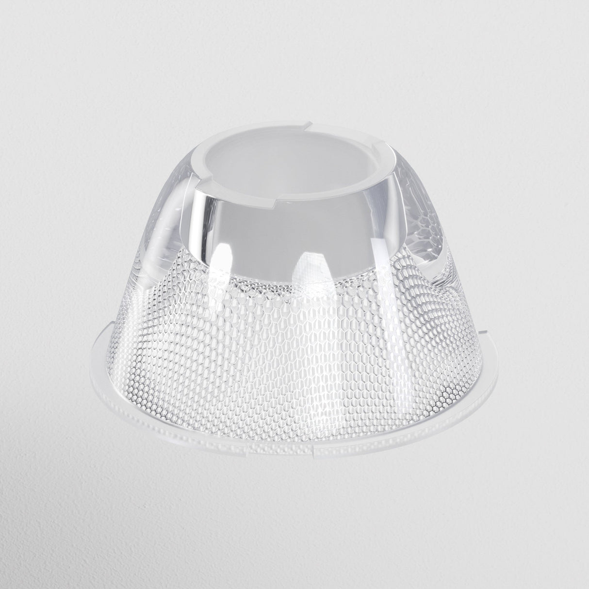 A clear, textured plastic dome with a hexagonal pattern and open top sits against a plain light gray background, its reflective surface mimicking the intricate design of the Focus LED Track Light Lens ⌀35mm 36°, adding depth to its captivating structure.