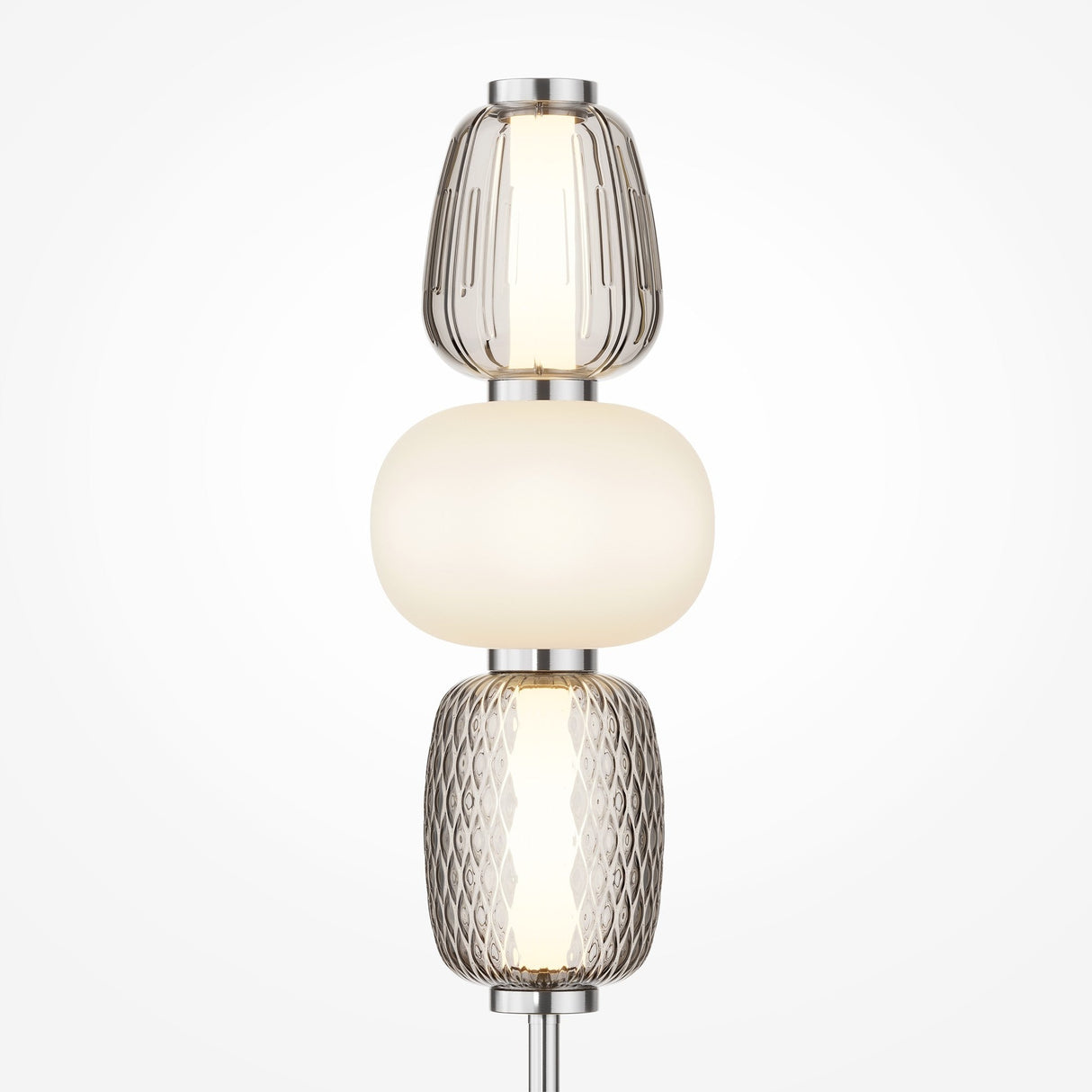 The Pattern LED Table Lamp - Chrome features three stacked glass sections: top and bottom are transparent with textures, the middle is opaque white. It emits a soft light with a chrome finish for a modern, elegant look.