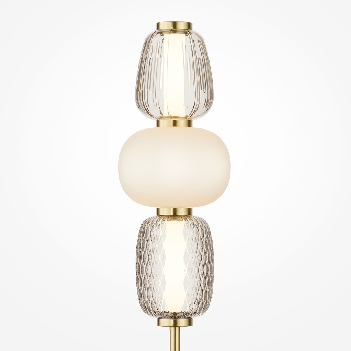 The Pattern LED Table Lamp - Gold features an energy-efficient design with a gold base and three vertically stacked glass shades. The top and bottom shades are textured, while the smooth, opaque middle shade provides a warm glow, enhancing the sleek gold metal finish.