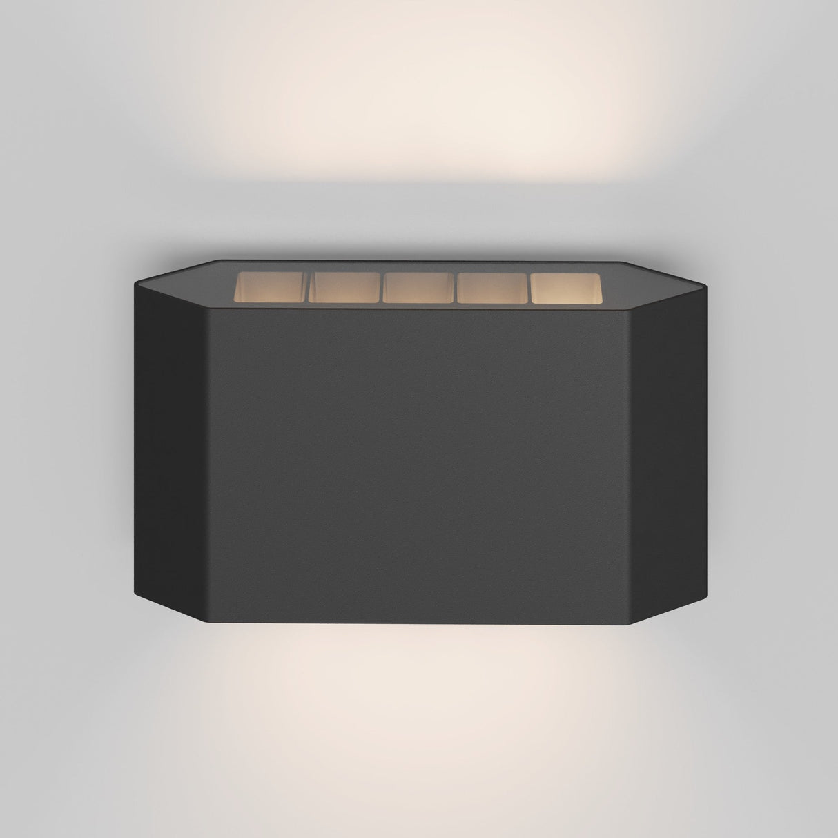 The Pull Outdoor LED Wall Light 8W 3000K - Graphite features a modern rectangular design with cutouts that emit soft directional lighting from the top and bottom, casting an ambient glow on any wall.