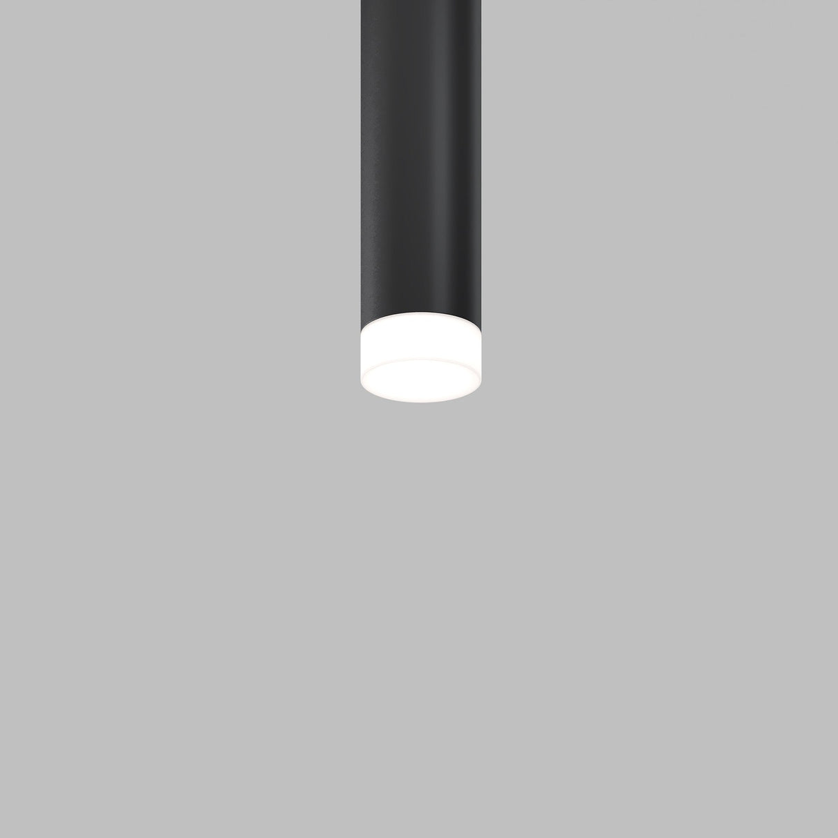 A minimalist black cylindrical ceiling light fixture with the Focus LED Light Diffuser Small 12W is illuminated against a plain gray background, creating a gentle white glow at the base.