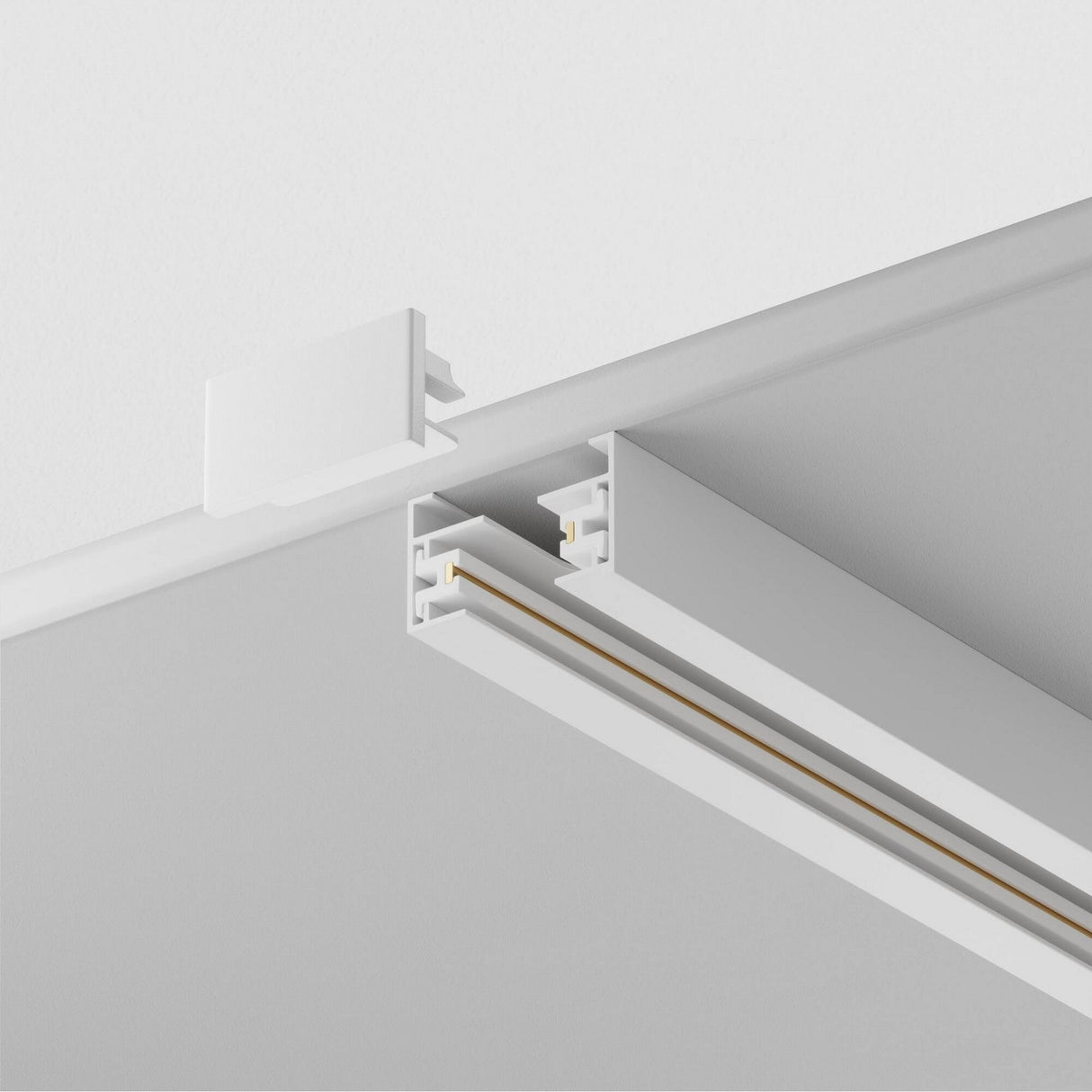 A close-up of a partially attached Unity Single Phase Surface-Mounted Track 2m in white reveals a sleek design with dual parallel gold-toned lines. An end cap matches the track, ideal for modern lighting projects.