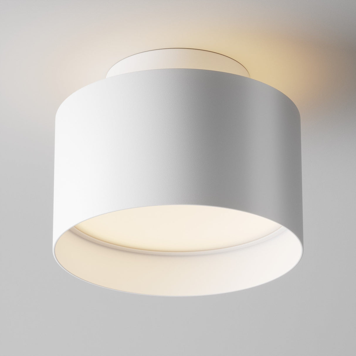 The Planet LED Medium Round Surface Downlight 3000K in white is a modern cylindrical fixture with an energy-efficient LED glow from beneath, illuminating the area. This sleek downlight is mounted directly to the ceiling.