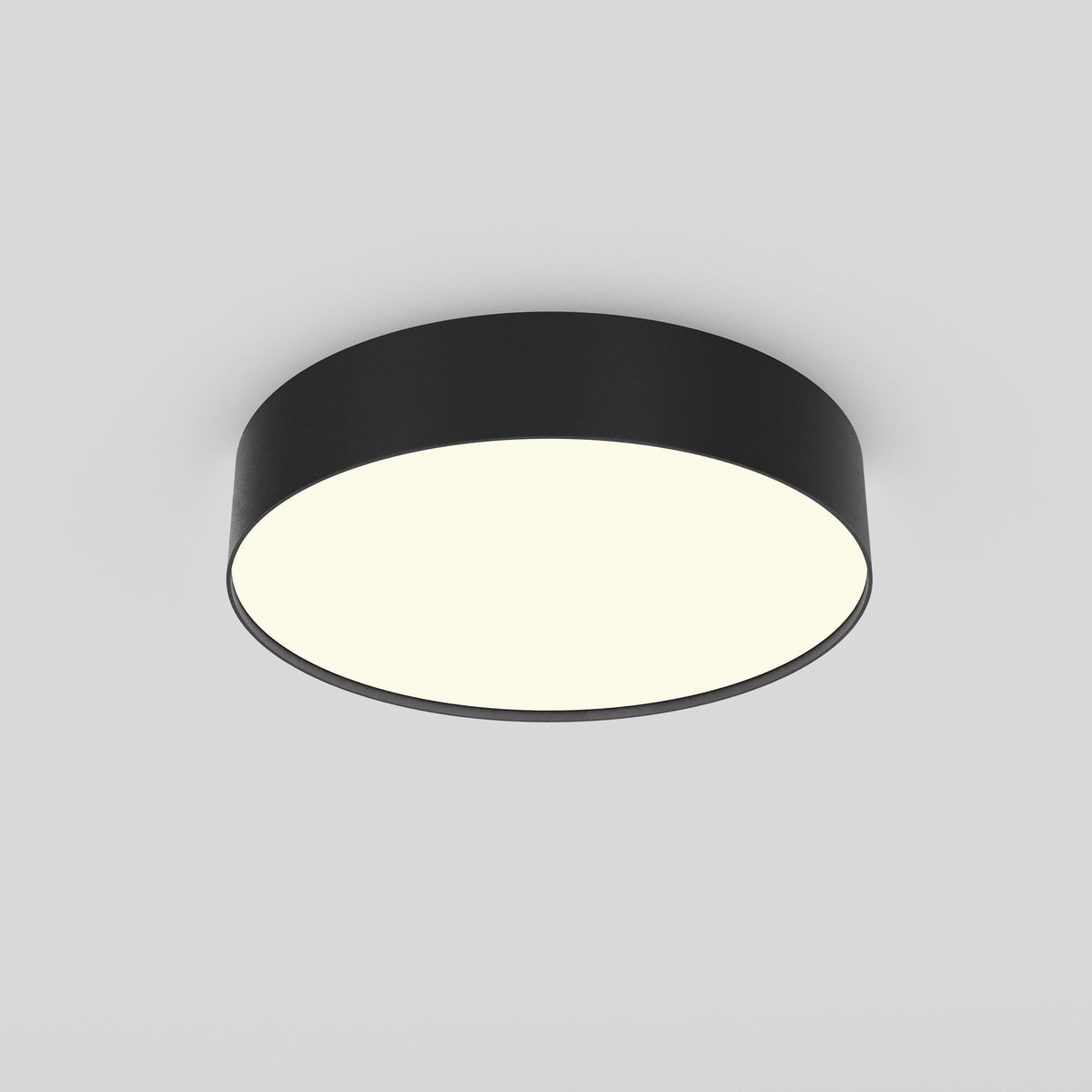 The Zon LED Small Flush Ceiling Light 3000K 26W in Black, with its sleek, modern design and flush-mounted style, is shown against a white ceiling. It emits a soft, uniform glow that highlights its modern elegance.