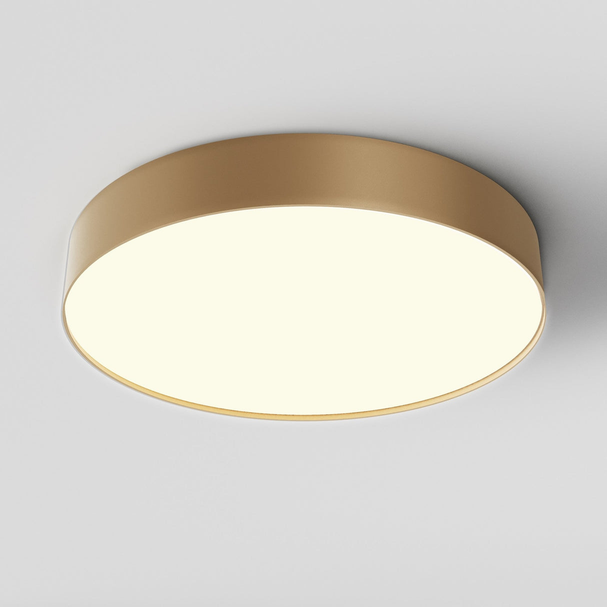 The Zon LED Medium Flush Ceiling Light 3000K 45W in matte gold emits a soft, bright glow against a plain white background for elegant ambient lighting.