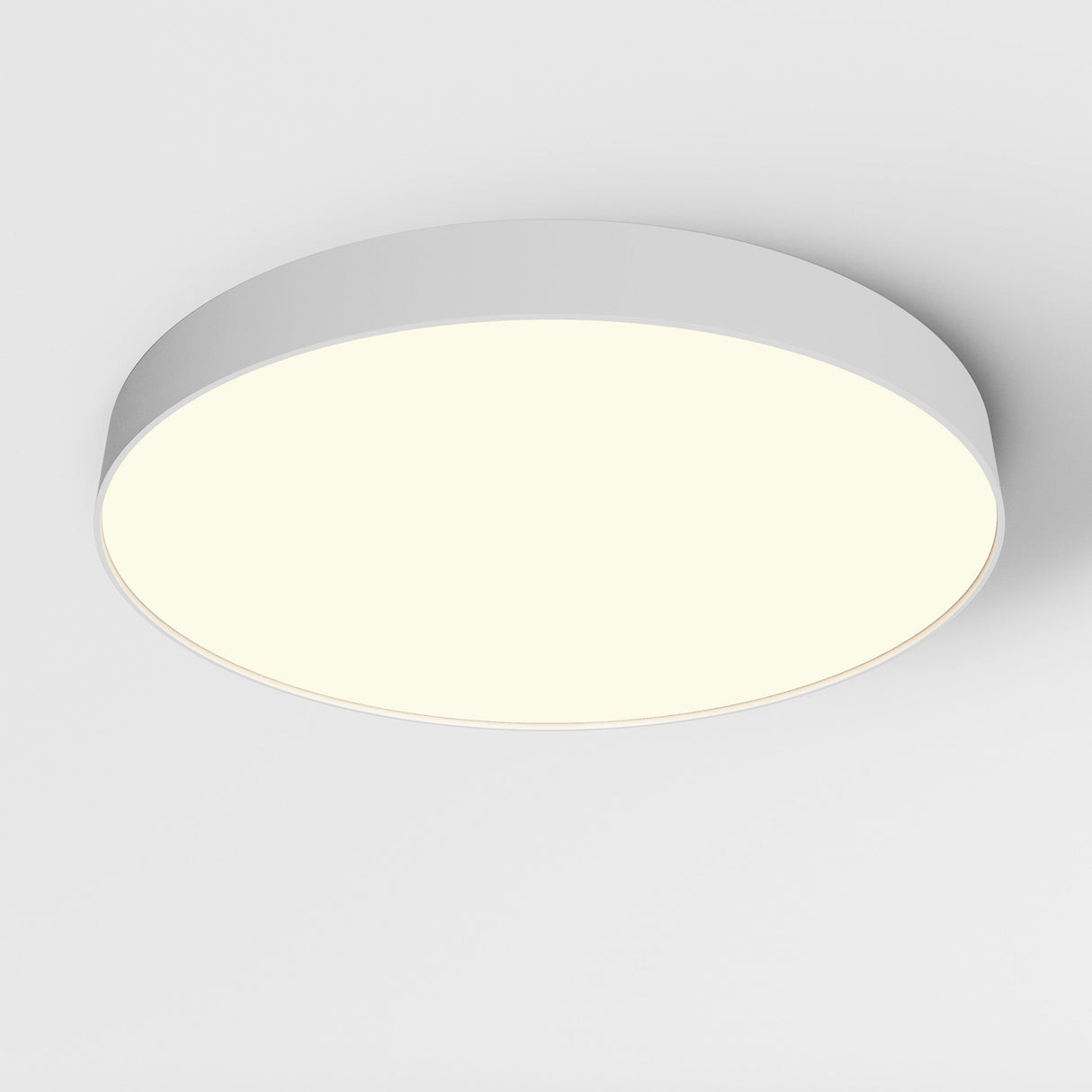 The Zon LED Large Flush Ceiling Light 3000K 90W - White, with its round design, is mounted on a white ceiling, blending seamlessly into the modern interior while emitting a soft, even glow that illuminates the area, embodying minimalist lighting design.