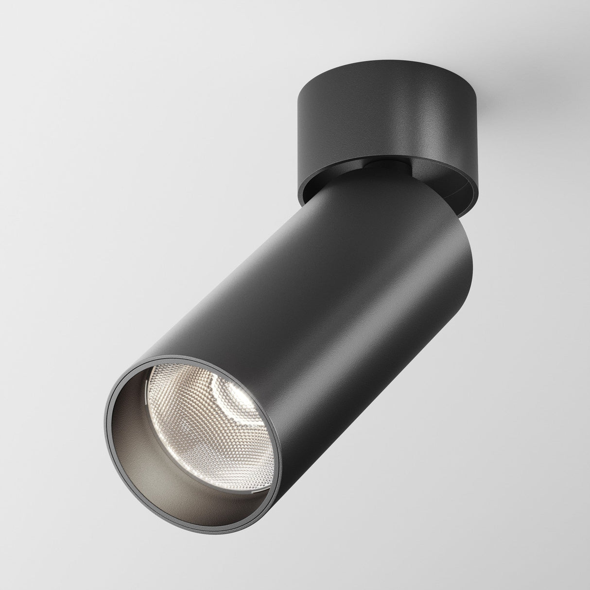 The Focus LED Single Surface-Mounted Spotlight, 12W, 4000K in black, features a modern cylindrical design and matching circular base for energy-efficient directional lighting on a plain white ceiling.