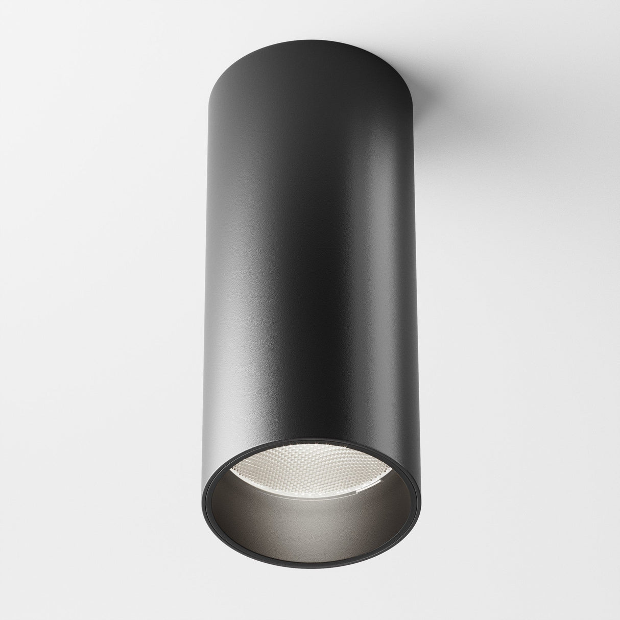 The Focus LED Fixed Round Surface Mounted Downlight 12W 4000K - Black features a modern cylindrical design with a matte finish. Installed on a white ceiling, its energy-efficient recessed bulb delivers neutral, focused illumination.