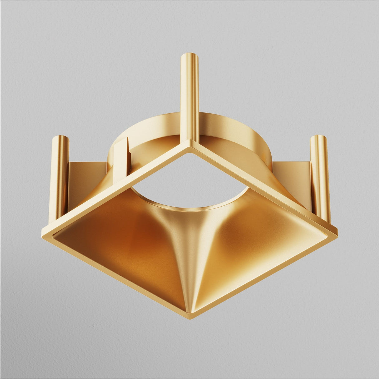 The Alfa LED Square Decorative Reflector Frame in matte gold elegantly features cylindrical rods and a diamond-shaped base with a central circular cutout, set against a plain gray background like an ornate geometric sculpture.
