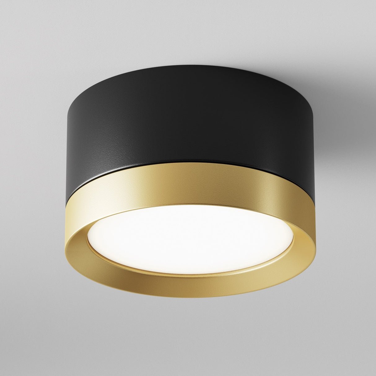 The Hoop Small Round Surface Downlight in black and gold is a modern interiors masterpiece with its sleek design. It features a matte black exterior, smooth gold edges, and beautifully diffused light on a white ceiling.