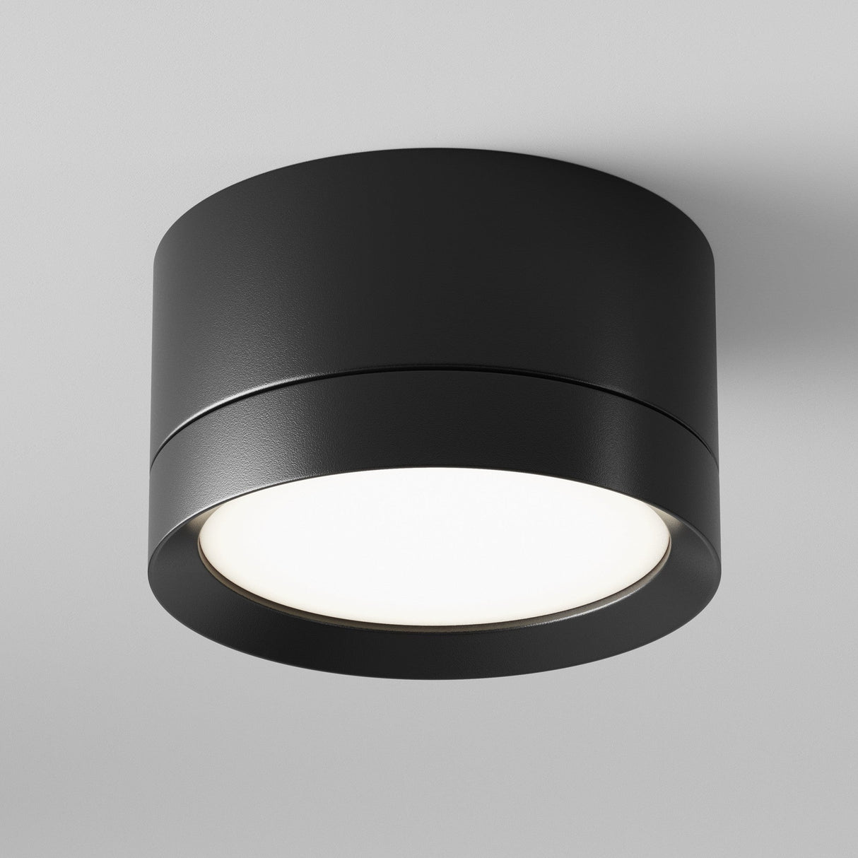 The Hoop Small Round Surface Downlight in black is a cylindrical LED fixture with a bright circular white light, providing an elegant modern accent on the smooth white ceiling.