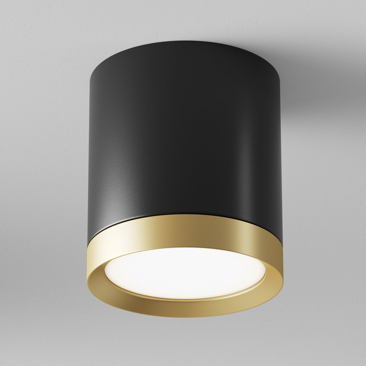 The Hoop Medium Round Surface Downlight in Black & Gold is a chic lighting fixture with a cylindrical shape, matte black finish, and gold trim. Its an LED downlight that emits soft white light and mounts seamlessly on a white ceiling.