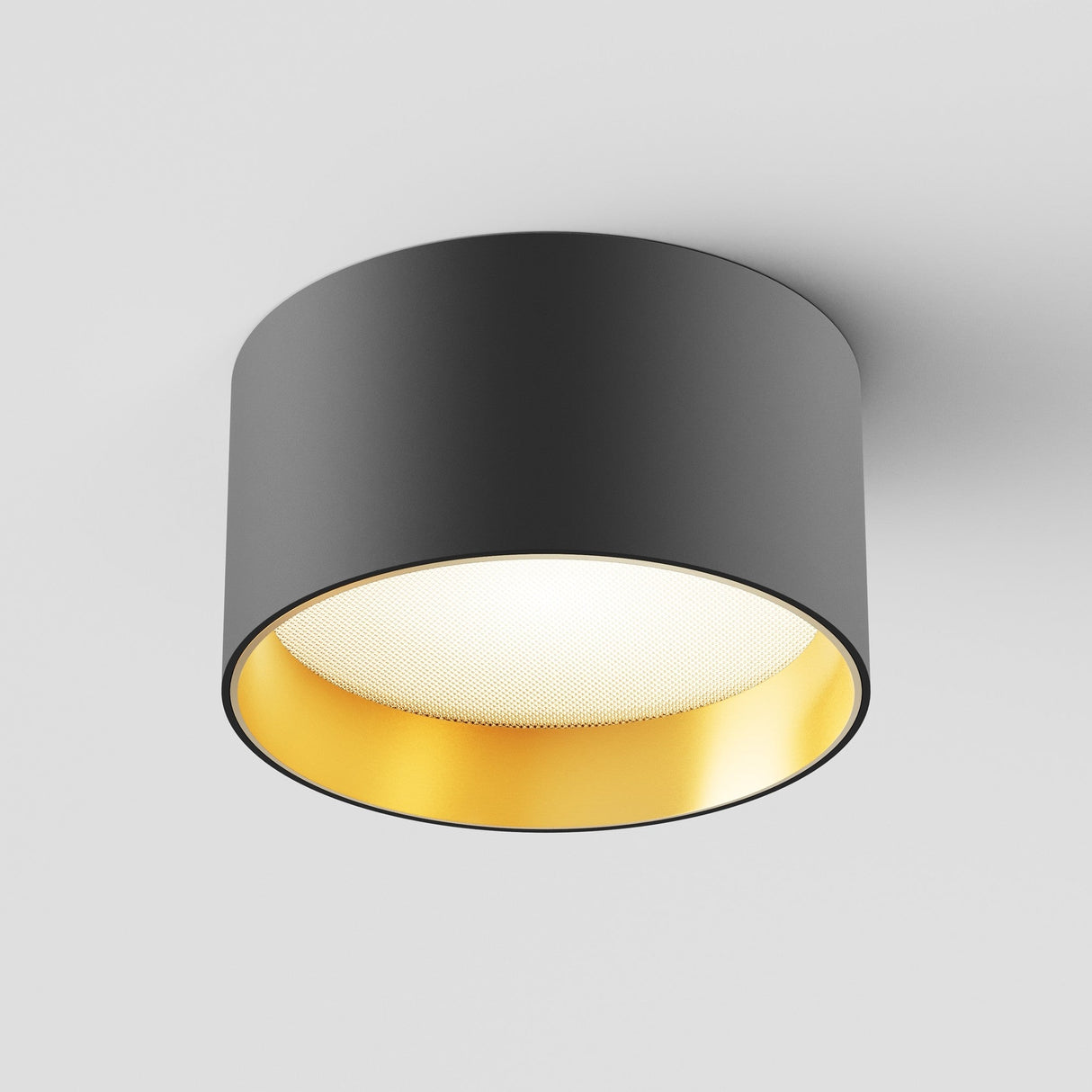 The Vega LED Round Surface Downlight 12W 3000K in black and matte gold offers high CRI lighting for excellent color rendering. Its reflective gold interior casts a warm glow, while its cylindrical design blends seamlessly with any smooth white ceiling.