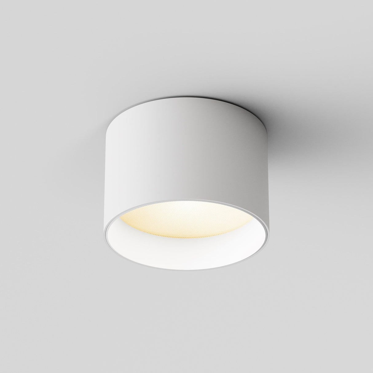 The Vega LED Round Surface Downlight 8W 3000K in white features a modern cylindrical design, offering energy-efficient lighting with a minimalist appeal. It emits a warm glow and is seamlessly mounted on a plain white ceiling.