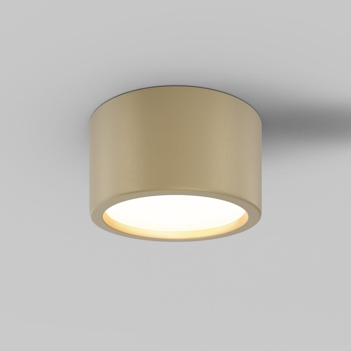 The Hydra LED Round Surface Downlight 15W 3000K in matte gold elegantly casts a soft, warm glow on the plain white ceiling. Rated IP44, it features a smooth finish.