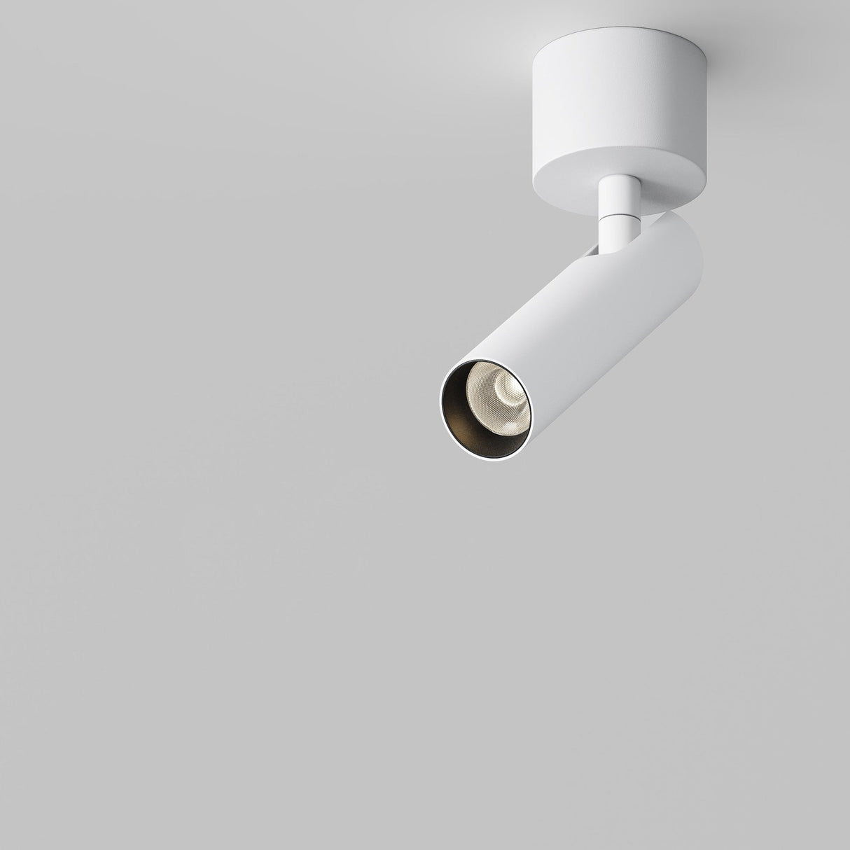 The Focus T LED Short Single Spotlight 6W 3000K in white, with a modern cylindrical design, is mounted against a plain gray background. Its energy-efficient build angles the light downward, showcasing its minimalist elegance.