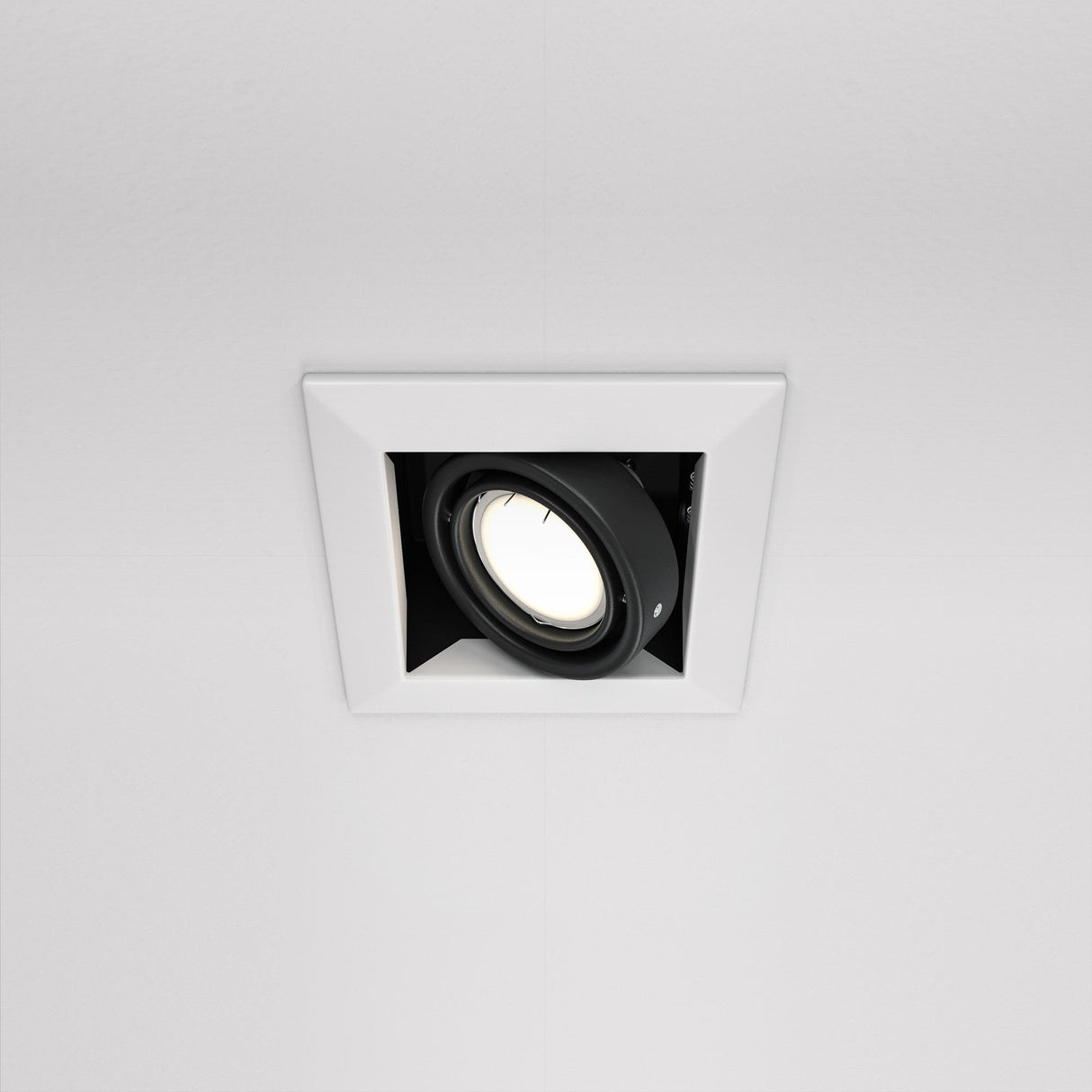The Metal Modern Single Tilt Square Recessed Downlight - White is embedded in the ceiling, casting a soft glow. Its modern design seamlessly merges with the decor, providing both elegance and functionality.