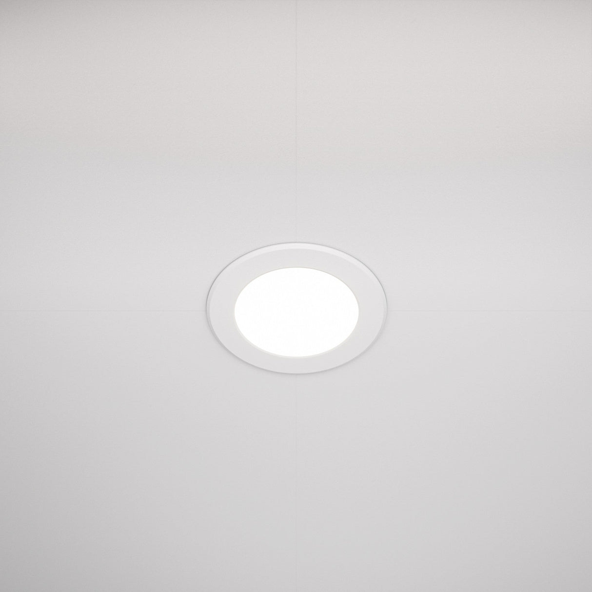 The Stockton CCT LED Round Recessed Downlight 7W 3000-6000K - White is centrally mounted on a neutral white ceiling. It emits a soft glow and thin lines from ceiling panels converge at the fixture, enhancing its energy-efficient design symmetrically.