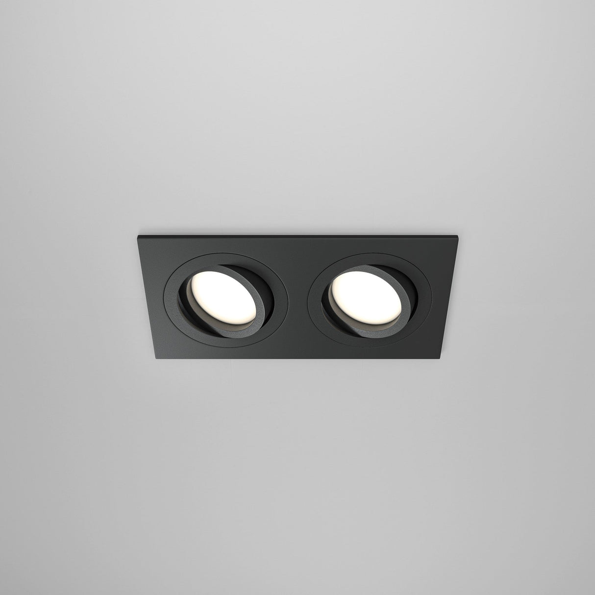 The Atom Twin Tilt Rectangular Recessed Downlight in black features a sleek frame with twin adjustable light heads, perfect for a modern white ceiling.