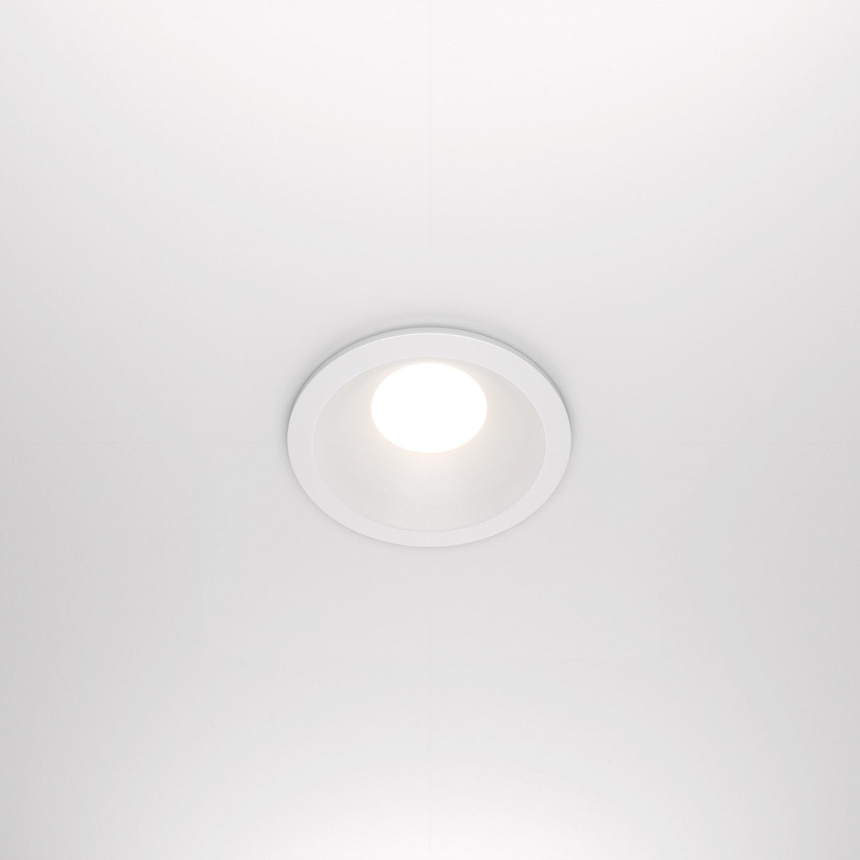 The Zoom Single Fixed Round Recessed Downlight in white is a ceiling-mounted LED with an IP65 rating, emitting bright white light against a smooth white ceiling.