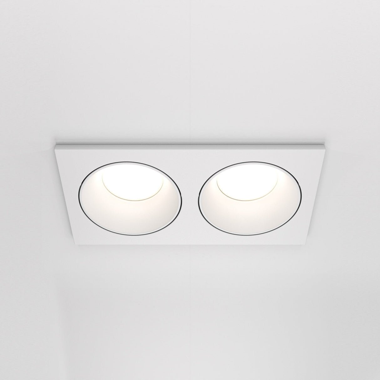 The Zoom Twin Fixed Rectangular Recessed Downlight in white delivers a modern look with two circular lights, casting a soft glow across the ceiling.