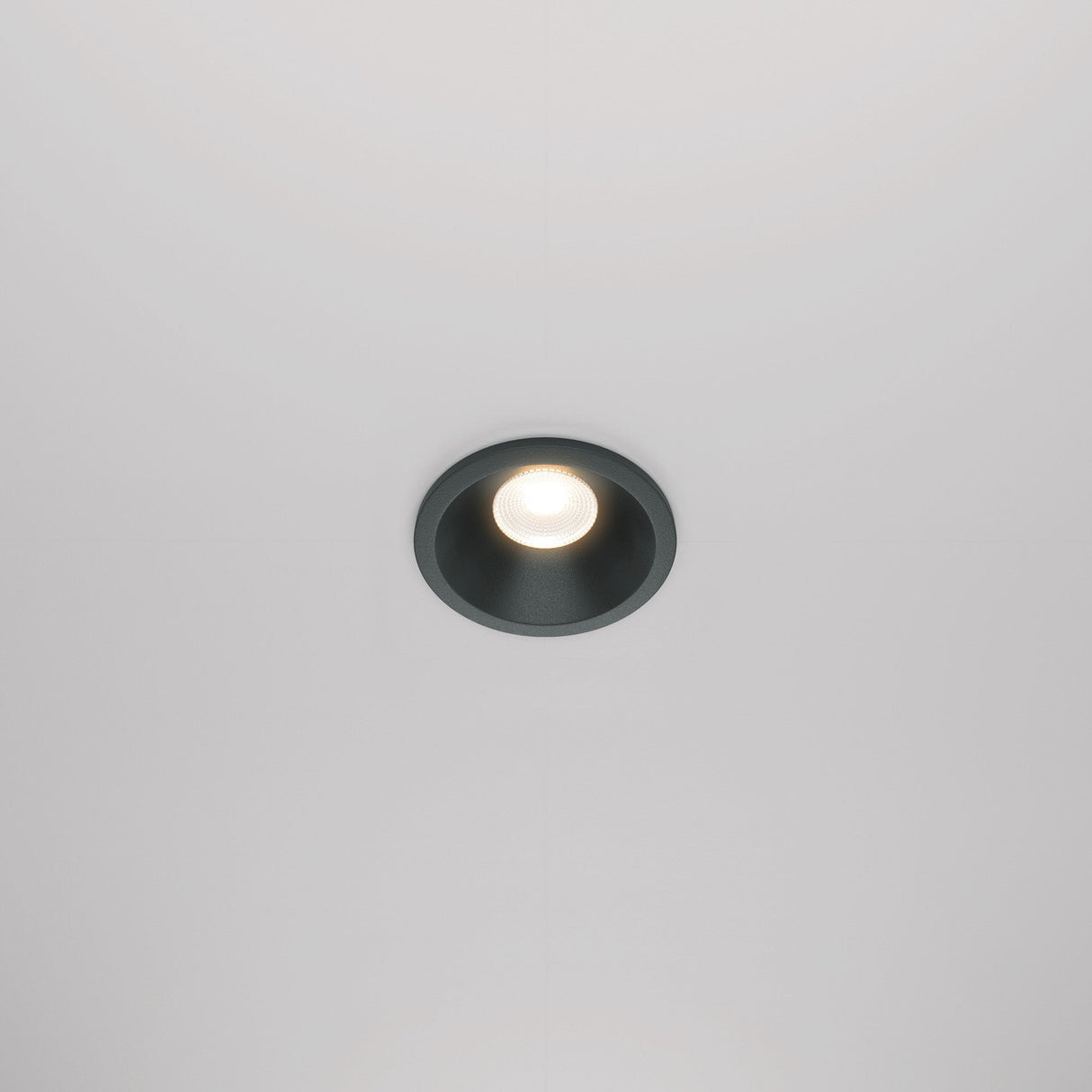 The Zoom LED Round Recessed Downlight 6W 3000K in black casts a soft glow on the plain white ceiling, creating an elegant atmosphere.