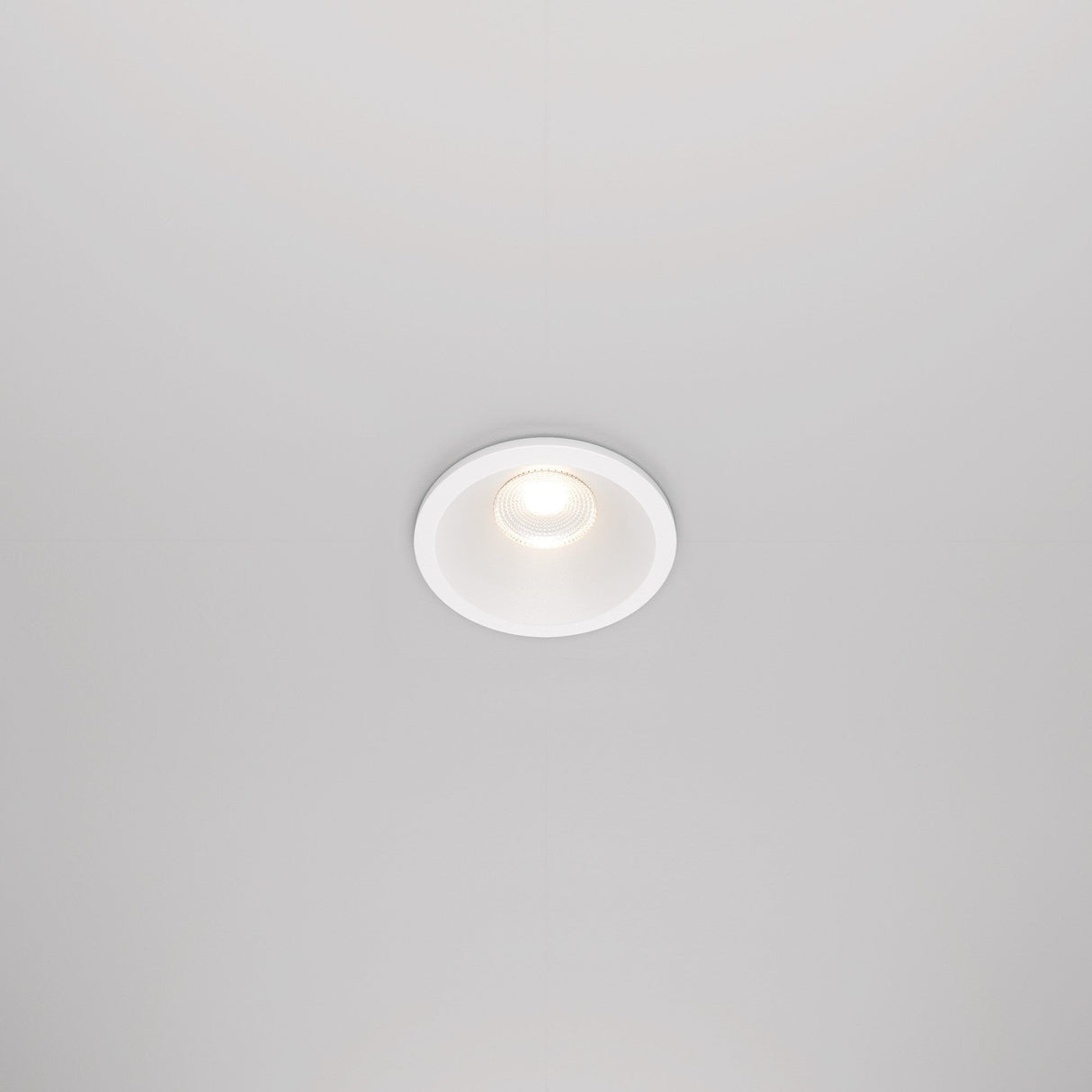The Zoom LED Round Recessed Downlight 6W 3000K in white is set into the ceiling, casting a soft, focused glow. This circular fixture features a white trim and an IP65 rating for durability, while retaining a minimalist and modern look.