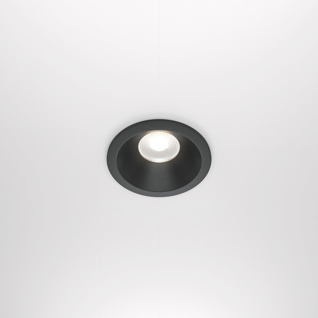 The Zoom LED Dimmable Round Recessed Downlight (12W, 4000K, IP65) is turned on, emitting a bright white glow. This circular light with a black trim is set in a plain white ceiling.