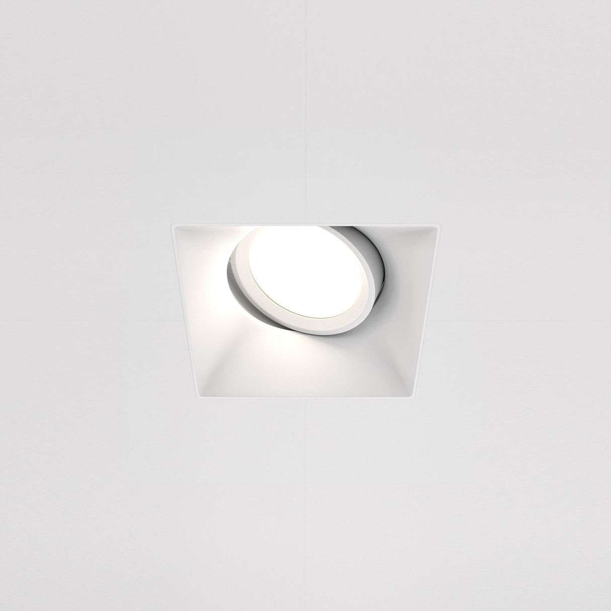 The Dot Single Tilt Plaster-in Square Recessed Downlight in white features a modern design with a clean finish. Its slightly angled structure allows adjustable light direction, offering focused illumination perfect for any contemporary space.