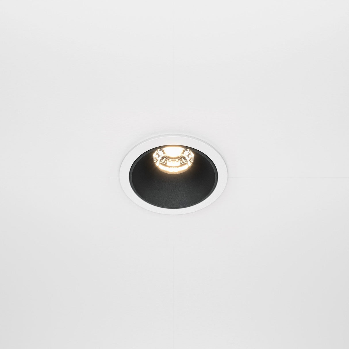 The Alfa LED Dimmable Fixed Round Recessed Downlight 10W 3000K - White & Black casts a warm glow on a plain white ceiling, enhancing the contemporary interior with its modern and sleek design.