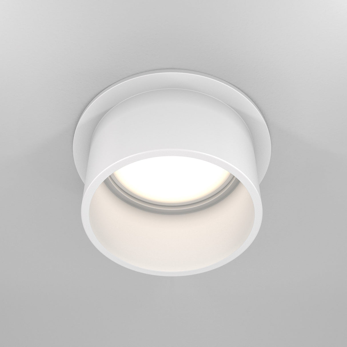 The Reif Round Recessed Downlight with Extended Rim - White is elegantly illuminated and seamlessly fits into a smooth, light-colored ceiling.