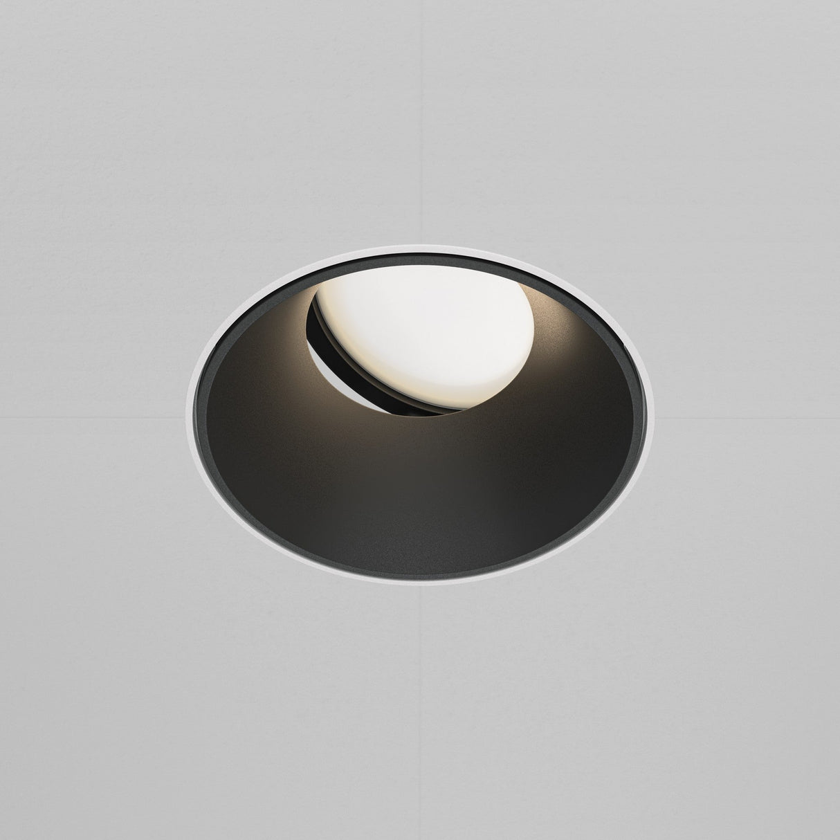 The Share Round Plaster-in Recessed Swivel Downlight in White & Black features a circular ceiling light with a white bulb inside a dark cylindrical fixture, designed for plaster-in installation against a plain, light-colored ceiling.