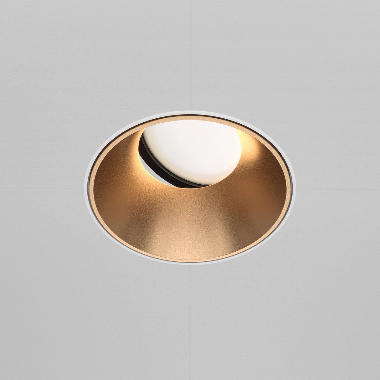 The Share Round Plaster-in Recessed Swivel Downlight in White & Matte Gold features a smooth, golden interior with an adjustable swivel design for versatile illumination and a soft, warm reflection against a gray surface.