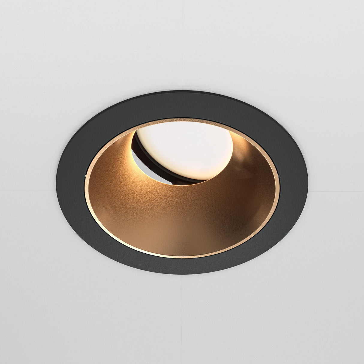 Close-up of the Share Round Recessed Swivel Downlight in black and matte gold, featuring a gold-toned interior that casts a warm glow. Its modern, minimalistic design contrasts elegantly with a pristine white ceiling for a sleek look.